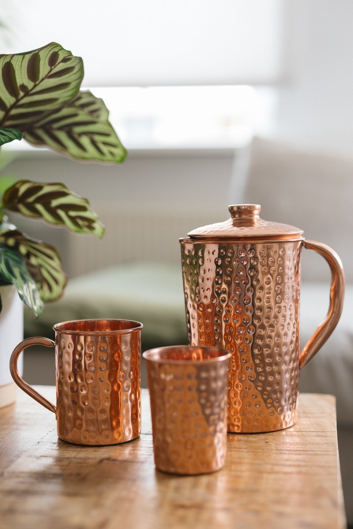 Kopero Copper Jug Hammered, with a mug and a cup on a wooden table