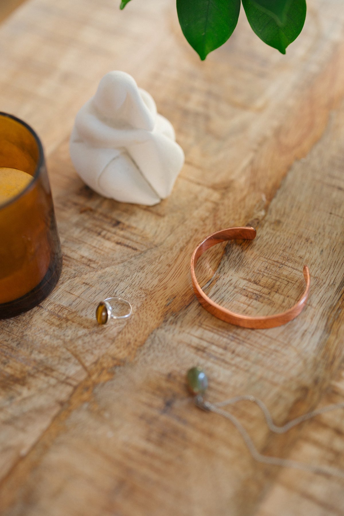 Kopero Copper Bracelet Smooth, on a wooden table next to a figurine and a ring