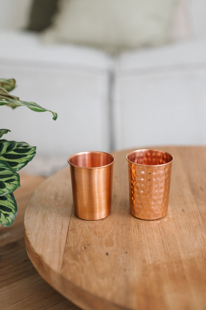 Kopero Copper Cup, a smooth and a hammered cup side by side on a round wooden table
