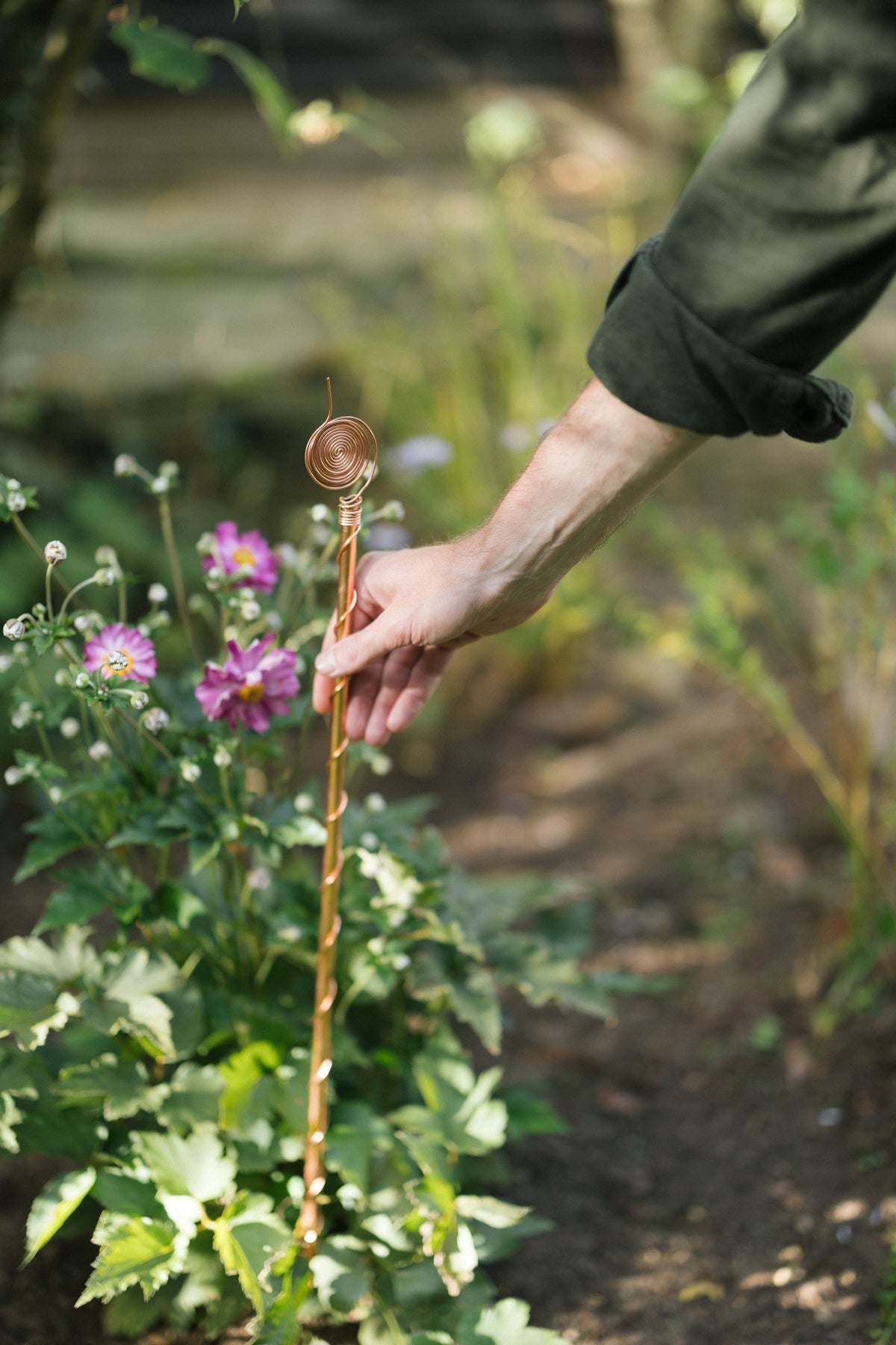 Kopero Electroculture 60 cm, a hand pushes the antenna into the flower bed