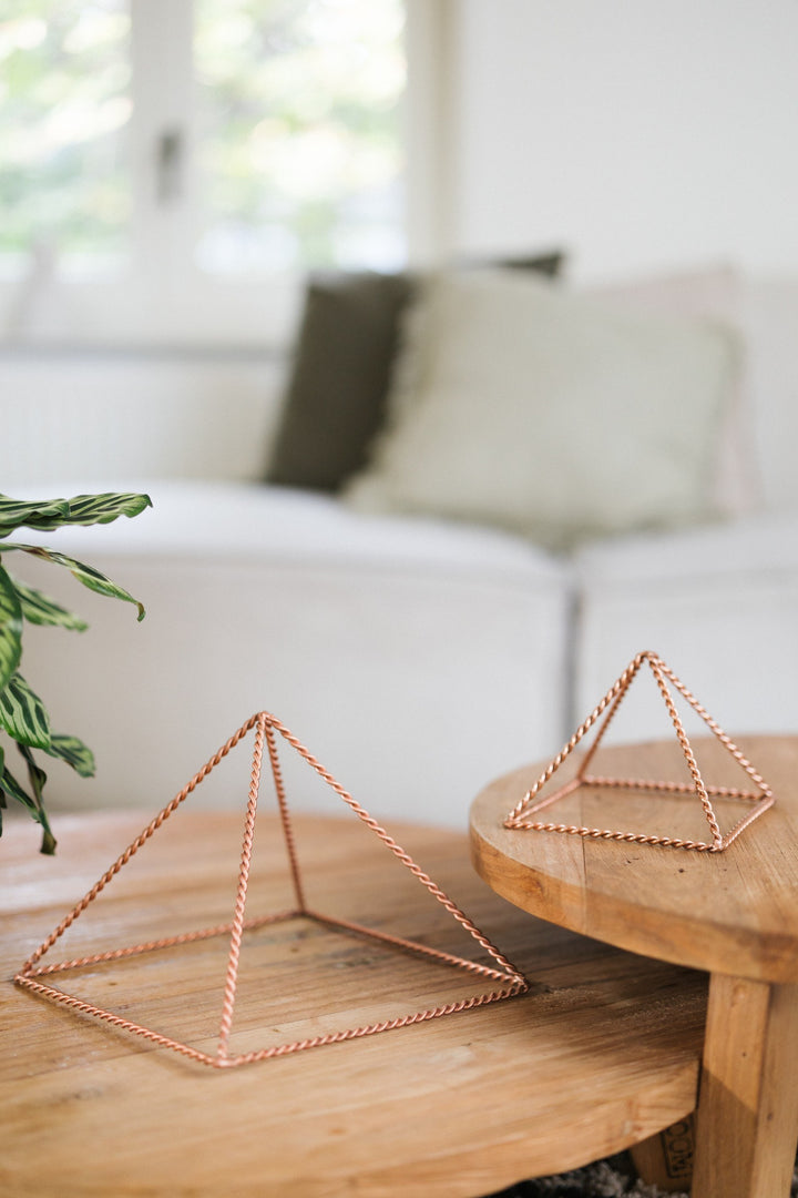 Kopero Copper Pyramid Energizer Twisted, the small and the large pyramid side by side on two wooden tables