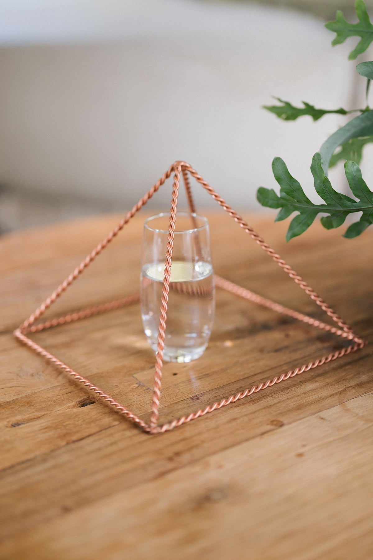 Kopero Copper Pyramid Energizer Twisted Large (23.56 cm), with a glass of water underneath