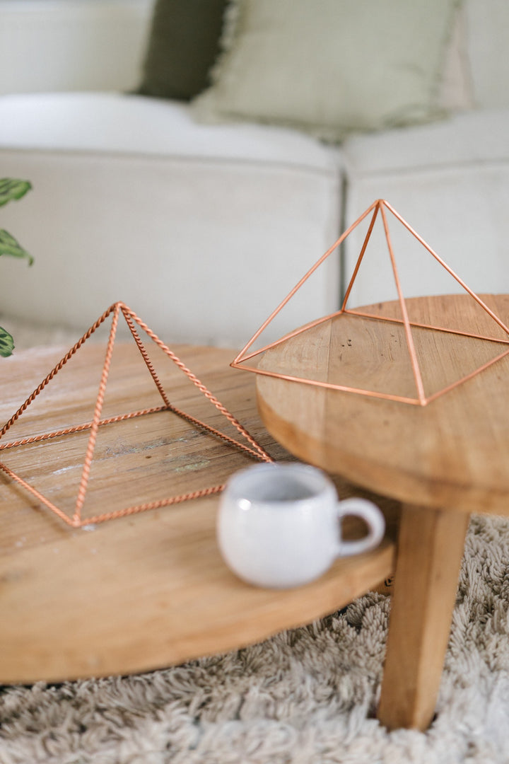 The large smooth and the large twisted pyramid on two wooden tables, with a mug