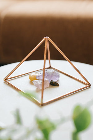 Kopero Copper Pyramid Energizer Smooth Small (14.56 cm), with gemstones underneath on a small white table