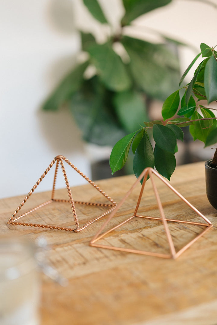 The small smooth and the small twisted pyramid side by side on a wooden table