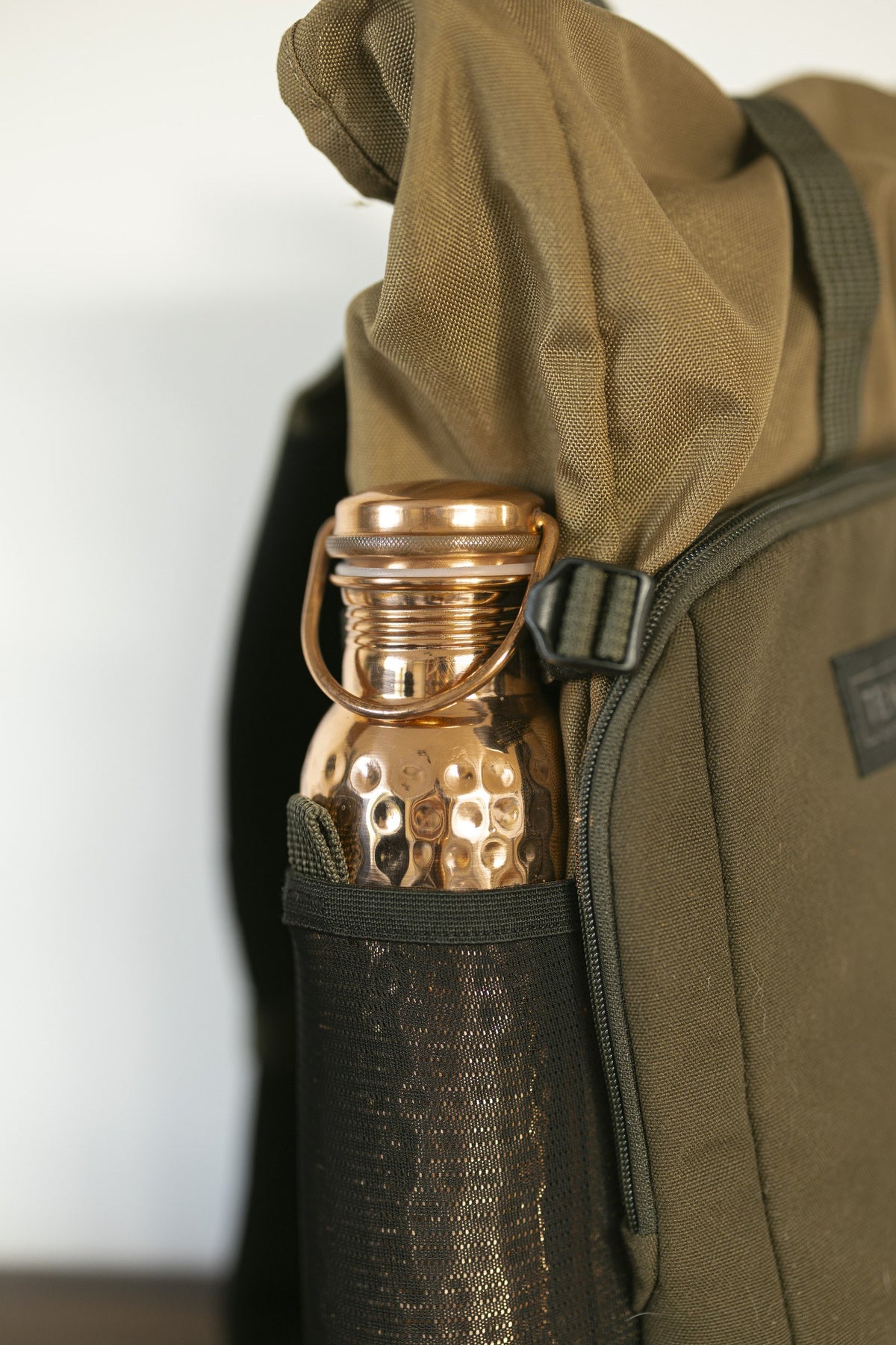 Kopero Copper Water Bottle Hammered, in the bottle pocket of a backpack